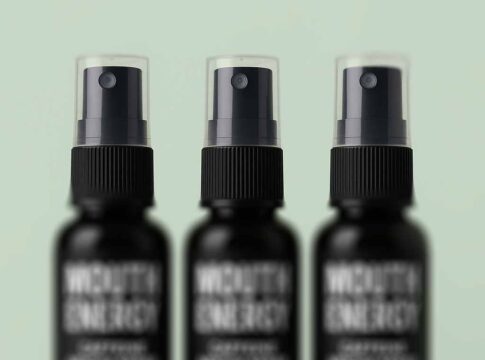 Drei Flaschen Mouth Energy Koffein-Mundspray in den Geschmacksrichtungen Menthol, Guave und Cola stehen nebeneinander auf grünem Hintergrund. Die Flaschen sind schwarz. Auf dem Etikett steht eine weiße Zahl. Die Zahl zeigt die Geschmacksrichtung an.