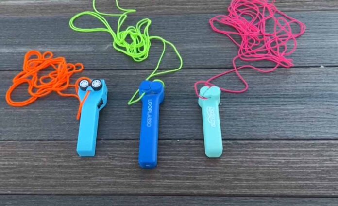 Drei Lasso-Spielzeuge im Test: No-Name, LOOP LASSO und ZIPSTRING mit verschiedenen Schnüren auf Holztisch